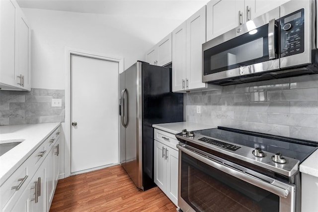 2313 Palm Ave, Seffner, FL 33584 - kitchen with stainless steel appliances, decorative backsplash, light countertops, light wood-style flooring, and white cabinetry