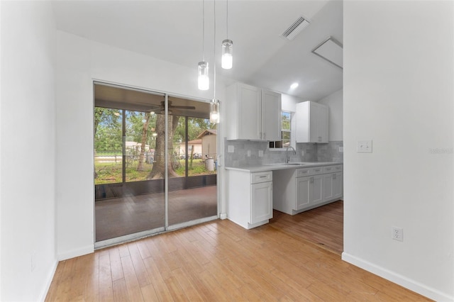 2313 Palm Ave, Seffner, FL 33584 - kitchen featuring a sink, light countertops, backsplash, light wood-style flooring, and white cabinets