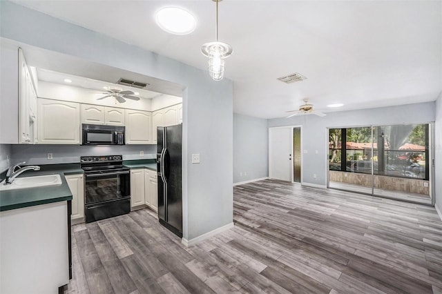 2770 Keats Ter Unit C, Palm Harbor, FL 34684 - kitchen with black appliances, a sink, a ceiling fan, dark countertops, and wood finished floors