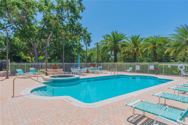 1126 Haley Ln, Dunedin, FL 34698 - view of swimming pool with a patio area, view of wooded area, and a pool with connected hot tub