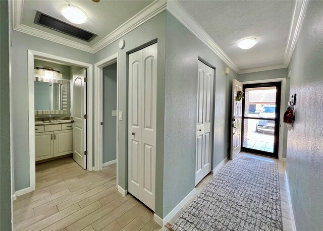 7360 Ulmerton Rd Unit 16A, Largo, FL 33771 - hall with a textured wall, a textured ceiling, light wood finished floors, ornamental molding, and baseboards