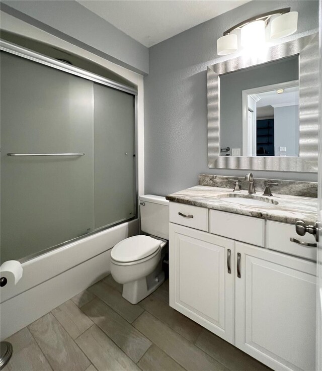 7360 Ulmerton Rd Unit 16A, Largo, FL 33771 - full bathroom featuring toilet, vanity, a textured wall, and bath / shower combo with glass door