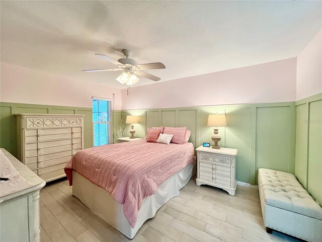 7360 Ulmerton Rd Unit 16A, Largo, FL 33771 - bedroom with a decorative wall, light wood-style floors, a ceiling fan, and wainscoting