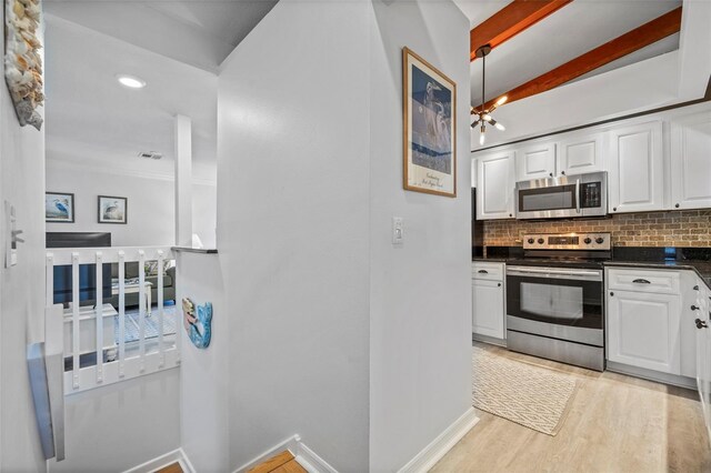 2665 Sequoia Ter Unit 306, Palm Harbor, FL 34683 - kitchen with appliances with stainless steel finishes, dark countertops, tasteful backsplash, white cabinets, and light wood-type flooring