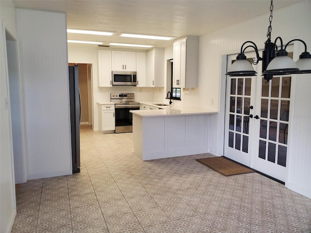 2615 Southern Oaks Pl, Plant City, FL 33566 - kitchen with appliances with stainless steel finishes, white cabinetry, a peninsula, light countertops, and french doors