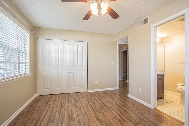 3002 W Cleveland St Unit C3, Tampa, FL 33609 - unfurnished bedroom featuring wood finished floors, a closet, multiple windows, a textured ceiling, and baseboards