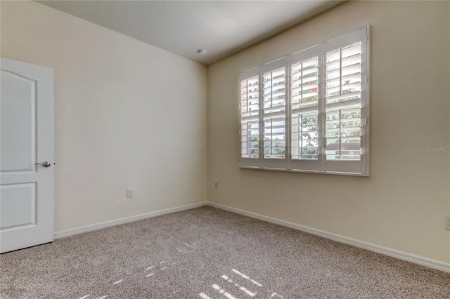 carpeted empty room featuring baseboards