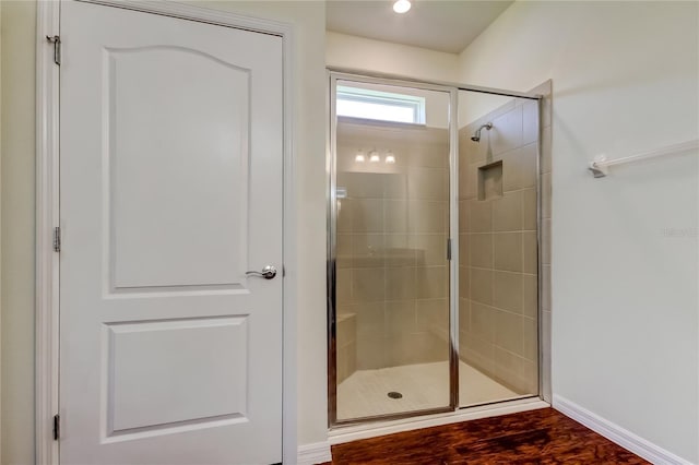 bathroom with a stall shower, baseboards, and wood finished floors