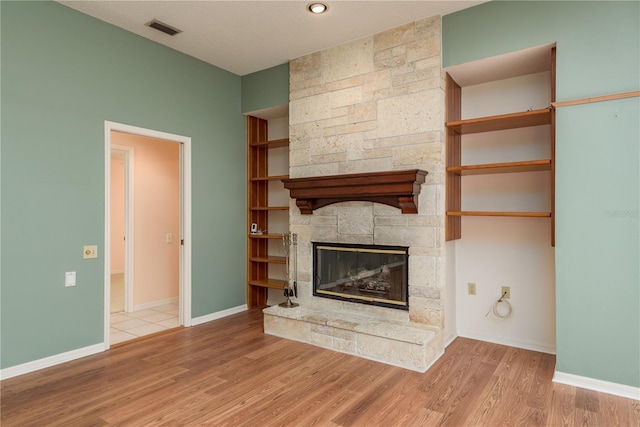 627 Belted Kingfisher Dr N, Palm Harbor, FL 34683 - unfurnished living room featuring a stone fireplace, wood finished floors, and baseboards
