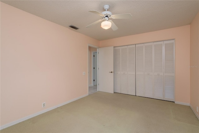 627 Belted Kingfisher Dr N, Palm Harbor, FL 34683 - unfurnished bedroom with light colored carpet, a closet, baseboards, ceiling fan, and a textured ceiling
