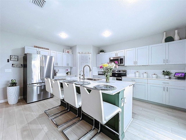 34056 Scarlet Sage Ct, Wesley Chapel, FL 33545 - kitchen with appliances with stainless steel finishes, a sink, light countertops, light wood-style flooring, and a center island with sink