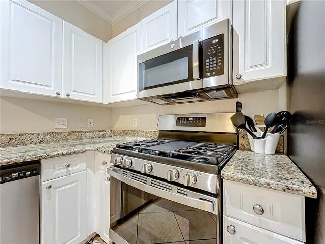 2724 Via Murano Unit 615, Clearwater, FL 33764 - kitchen featuring stainless steel appliances, ornamental molding, white cabinetry, tile patterned floors, and light stone countertops