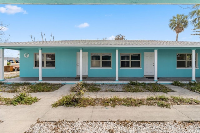 410 73rd Ave, St Pete Beach, FL 33706 - view of front of house featuring a porch, stucco siding, and roof with shingles