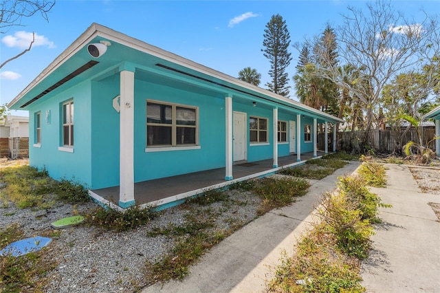 410 73rd Ave, St Pete Beach, FL 33706 - view of side of property with covered porch, fence, and stucco siding