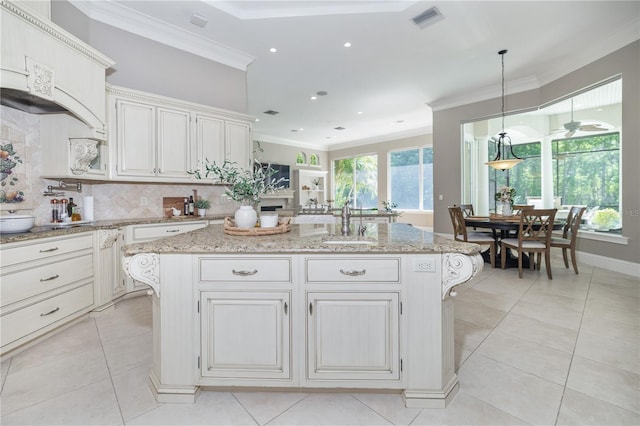 4512 Cheval Blvd, Lutz, FL 33558 - kitchen with a sink, a kitchen island, backsplash, crown molding, and light stone counters