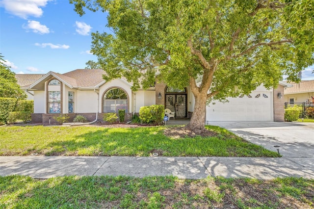 5434 Wellfield Rd, New Port Richey, FL 34655 - view of front of house with a garage, driveway, stucco siding, brick siding, and a front yard