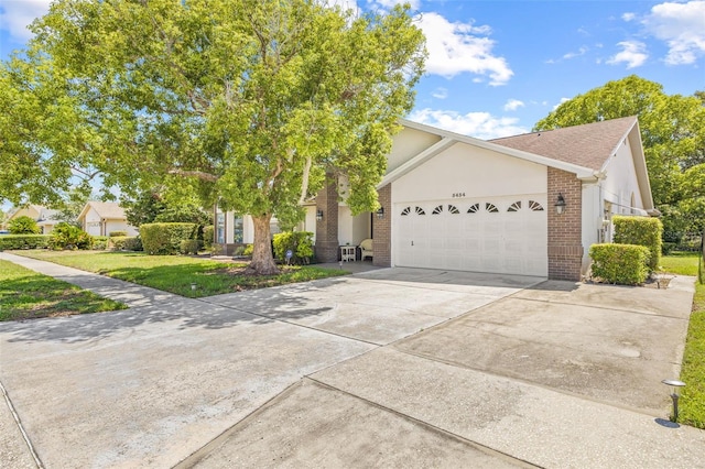 5434 Wellfield Rd, New Port Richey, FL 34655 - view of front facade featuring brick siding, a garage, driveway, a front lawn, and stucco siding