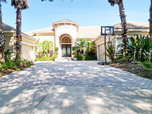 15101 Kestrelglen Way, Lithia, FL 33547 - mediterranean / spanish home featuring a garage, french doors, decorative driveway, and stucco siding