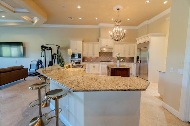 15101 Kestrelglen Way, Lithia, FL 33547 - kitchen with built in appliances, a large island with sink, a sink, a chandelier, and ornamental molding
