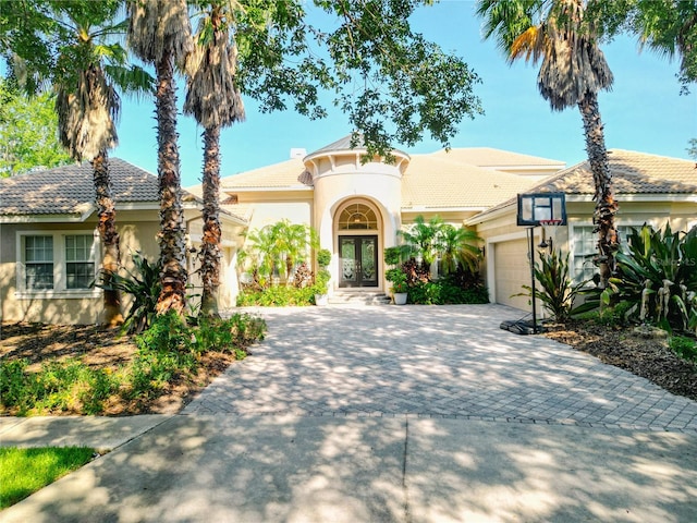 15101 Kestrelglen Way, Lithia, FL 33547 - mediterranean / spanish house with a garage, decorative driveway, stucco siding, french doors, and a tile roof