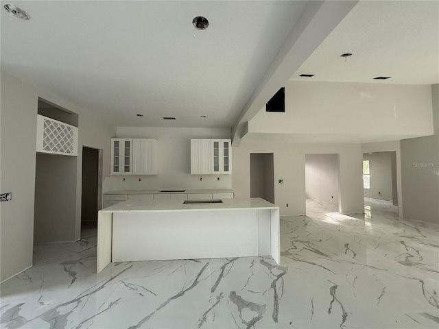 14273 Nugent Cir, Spring Hill, FL 34609 - kitchen with white cabinetry, glass insert cabinets, light marble finish floors, a spacious island, and light countertops