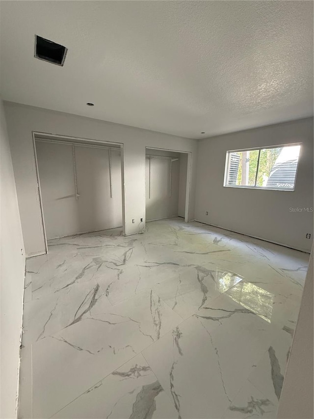 14273 Nugent Cir, Spring Hill, FL 34609 - unfurnished bedroom featuring multiple closets, a textured ceiling, and light marble finish floors
