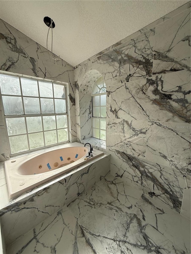 14273 Nugent Cir, Spring Hill, FL 34609 - bathroom featuring a tub with jets, a textured ceiling, marble finish flooring, and vaulted ceiling
