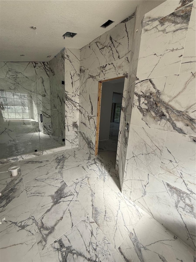 14273 Nugent Cir, Spring Hill, FL 34609 - bathroom featuring a marble finish shower, a textured ceiling, stone wall, and marble finish floors