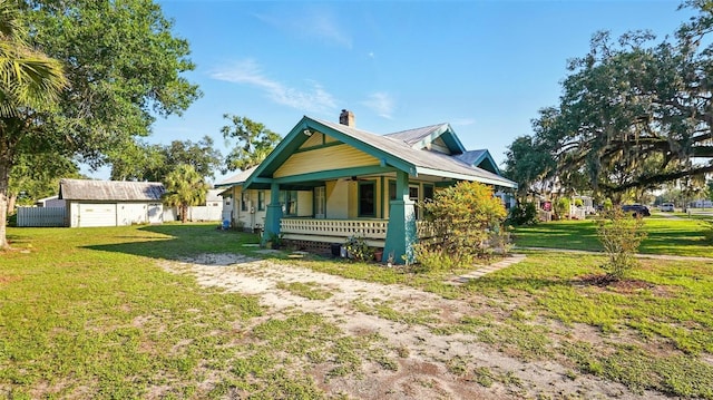 138 S Hernando Ave, Arcadia, FL 34266 - back of house featuring covered porch, a chimney, a lawn, and metal roof