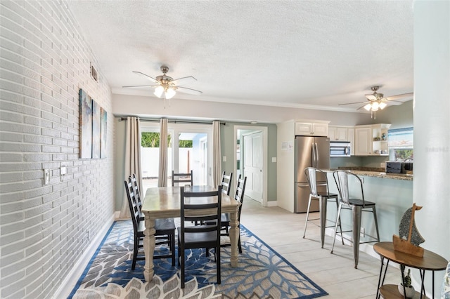 1818 Indian Rocks Rd S, Largo, FL 33774 - dining room featuring ceiling fan, a textured ceiling, brick wall, light wood finished floors, and baseboards