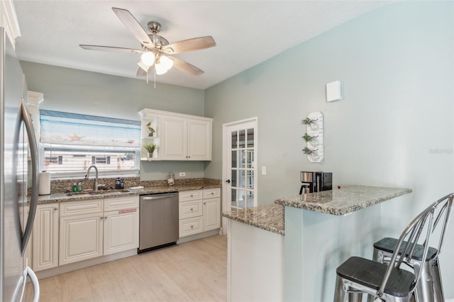 1818 Indian Rocks Rd S, Largo, FL 33774 - kitchen with stainless steel appliances, a sink, a peninsula, a breakfast bar, and light wood-style floors