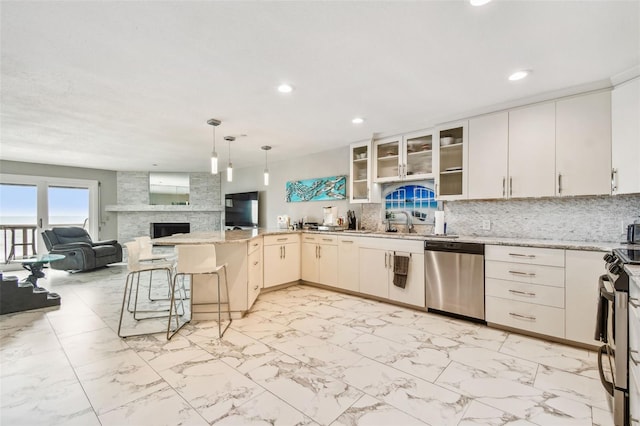 kitchen featuring appliances with stainless steel finishes, a peninsula, recessed lighting, light marble finish floors, and tasteful backsplash