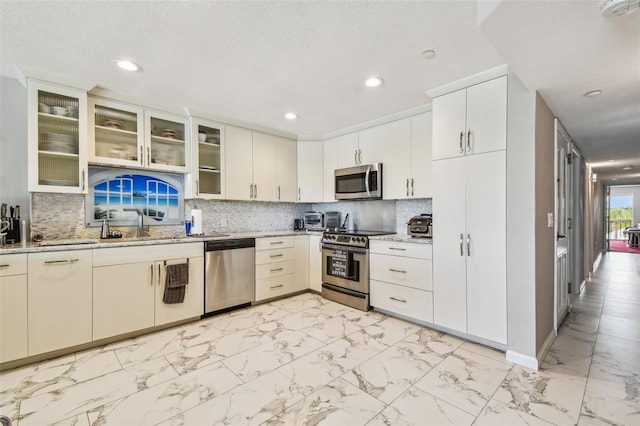 kitchen featuring stainless steel appliances, light marble finish flooring, recessed lighting, baseboards, and light stone counters