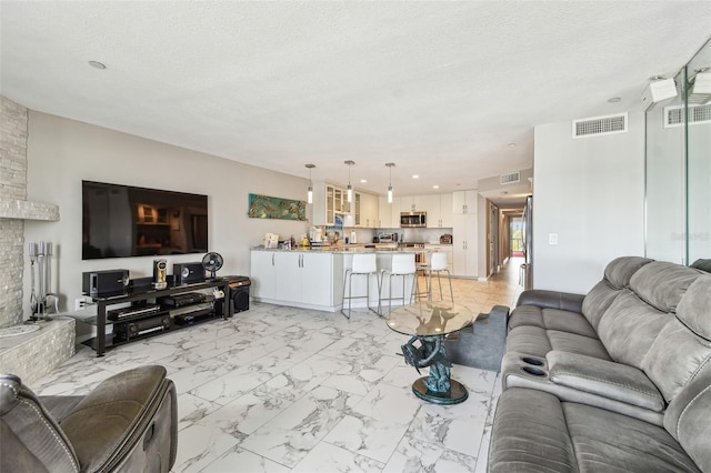 living area featuring light marble finish flooring and a textured ceiling