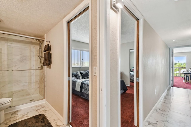 bathroom featuring ensuite bath, marble finish floors, a stall shower, baseboards, and a textured ceiling