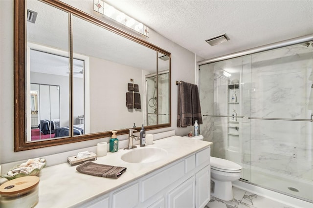 ensuite bathroom featuring a marble finish shower, marble finish floors, vanity, toilet, and a textured ceiling
