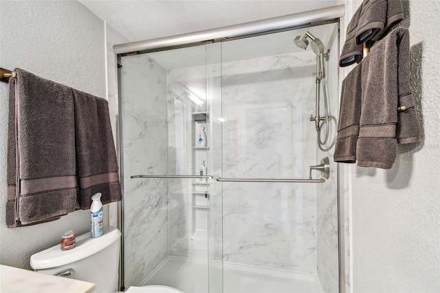 full bathroom with a textured wall, toilet, and a marble finish shower