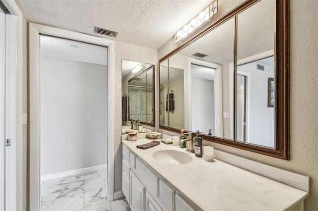 bathroom featuring marble finish floors, a textured ceiling, vanity, a textured wall, and baseboards