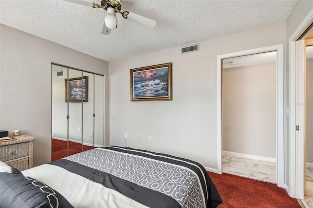 bedroom featuring a closet, a textured ceiling, a ceiling fan, baseboards, and marble look tile flooring