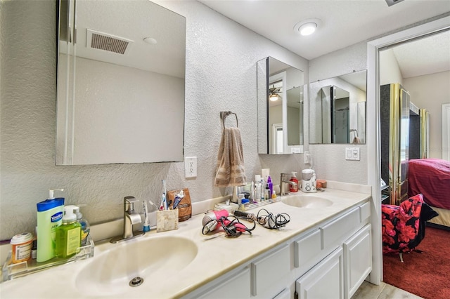bathroom featuring a textured wall, connected bathroom, and double vanity