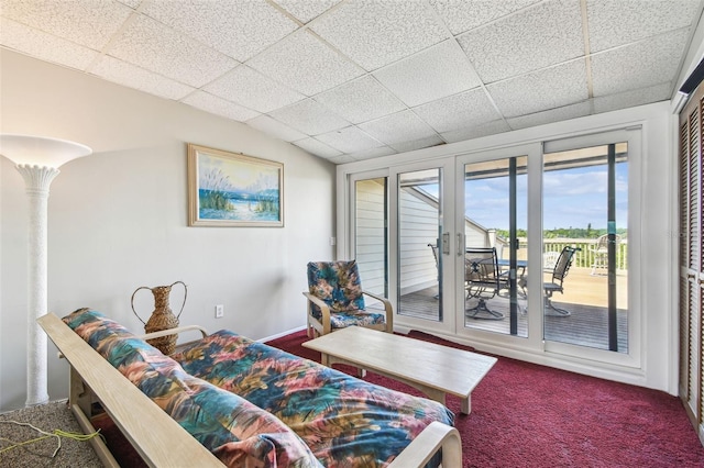 carpeted living area with a drop ceiling