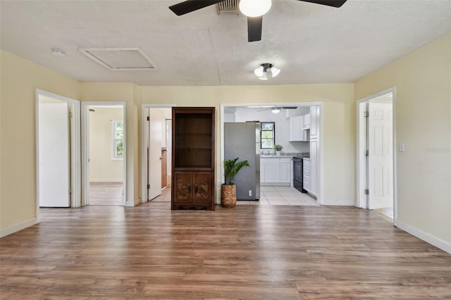 1810 77th Ave N, Saint Petersburg, FL 33702 - unfurnished living room featuring a ceiling fan, light wood-type flooring, baseboards, and a textured ceiling