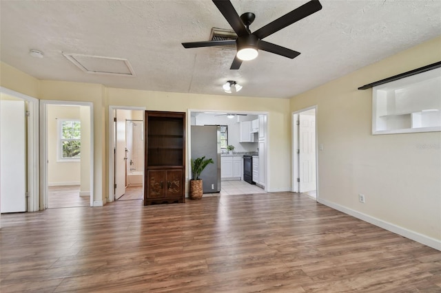 1810 77th Ave N, Saint Petersburg, FL 33702 - unfurnished living room featuring attic access, a textured ceiling, light wood-style flooring, healthy amount of natural light, and ceiling fan