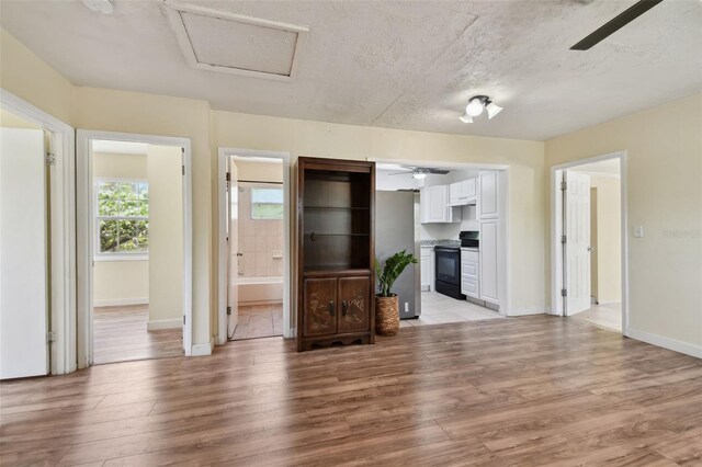 1810 77th Ave N, Saint Petersburg, FL 33702 - unfurnished living room with ceiling fan, light wood-type flooring, attic access, baseboards, and a textured ceiling