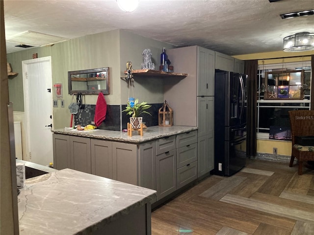 2912 Case Ave, Bradenton, FL 34207 - kitchen with black refrigerator with ice dispenser, gray cabinetry, a textured ceiling, light stone countertops, and open shelves