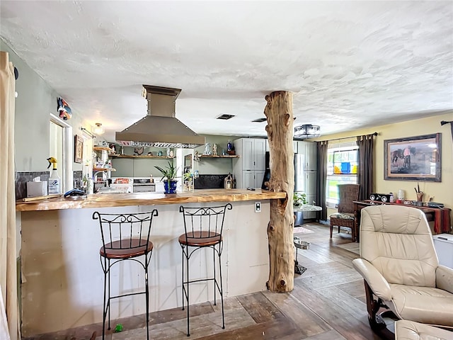 2912 Case Ave, Bradenton, FL 34207 - kitchen with island range hood, butcher block counters, open floor plan, hardwood / wood-style flooring, and a kitchen breakfast bar
