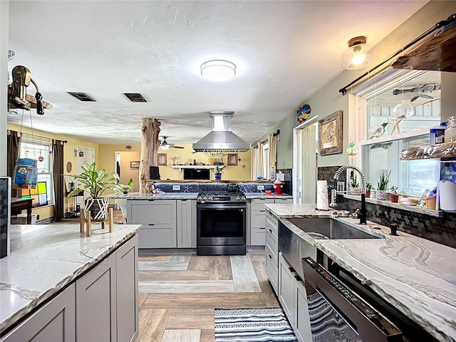 2912 Case Ave, Bradenton, FL 34207 - kitchen with gas stove, light stone countertops, gray cabinets, dishwasher, and island range hood