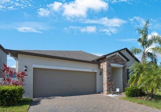 view of front facade with stucco siding, decorative driveway, an attached garage, and stone siding