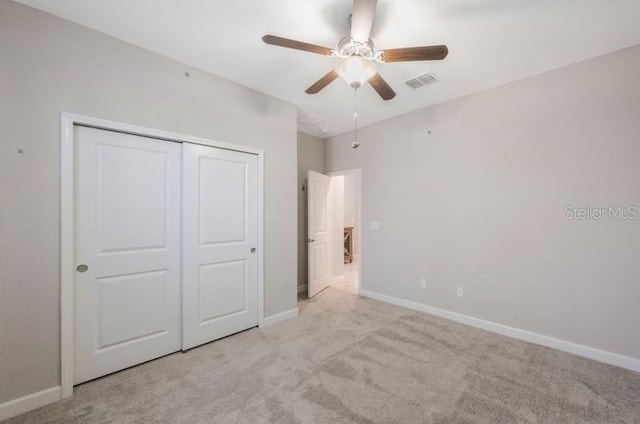 unfurnished bedroom with carpet flooring, baseboards, a closet, and a ceiling fan