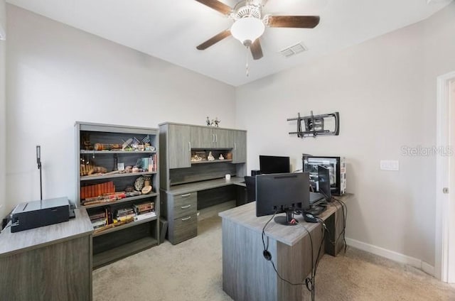 office space with light carpet, a ceiling fan, and baseboards